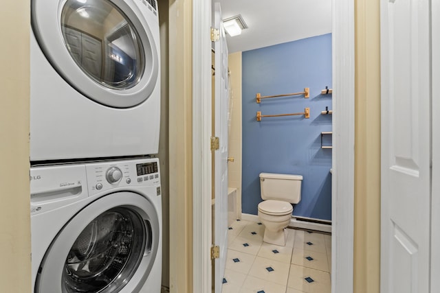 clothes washing area featuring stacked washer / drying machine, tile patterned flooring, a baseboard heating unit, and baseboards