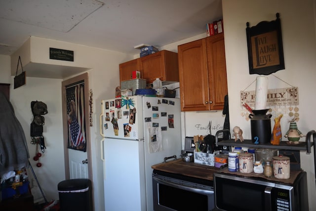 1003-1005 Main St, Vassalboro, ME 04989 - kitchen featuring stainless steel microwave, freestanding refrigerator, and brown cabinets