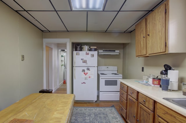 532 Main St, South Portland, ME 04106 - kitchen with white appliances, under cabinet range hood, wood finished floors, brown cabinets, and a paneled ceiling