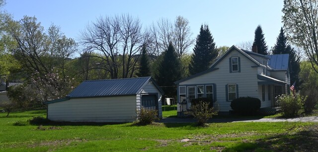 40 Baker St, Bingham, ME 04920 - view of home's exterior with an outdoor structure, a lawn, and metal roof