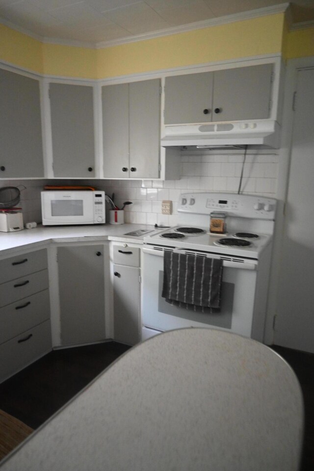 40 Baker St, Bingham, ME 04920 - kitchen with white appliances, under cabinet range hood, light countertops, crown molding, and decorative backsplash