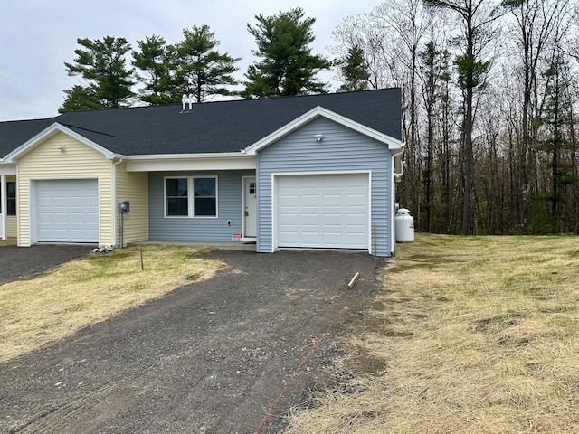 ranch-style home with a garage, asphalt driveway, and a front yard