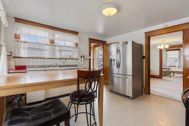 kitchen with stainless steel fridge with ice dispenser, tasteful backsplash, light countertops, and a sink
