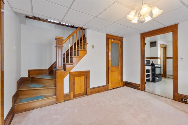 basement with stairs, a chandelier, baseboard heating, baseboards, and carpet flooring