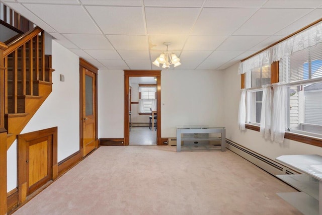 empty room featuring a chandelier, stairs, a paneled ceiling, carpet, and a baseboard heating unit