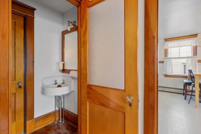 corridor featuring brick patterned floors, baseboards, and a baseboard radiator