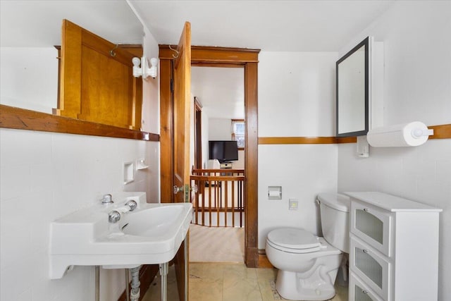 half bathroom featuring toilet and marble look tiles