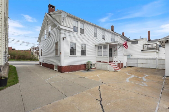 back of house with a chimney and fence