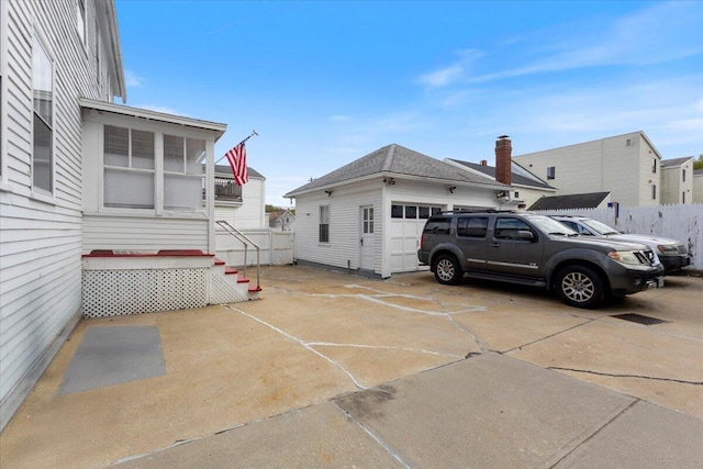 view of side of home with an attached garage, an outbuilding, and fence