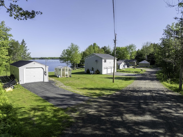 1824 Sunny Cove Ln, Meddybemps, ME 04657 - view of front of house with a detached garage, an outbuilding, a front yard, driveway, and a water view