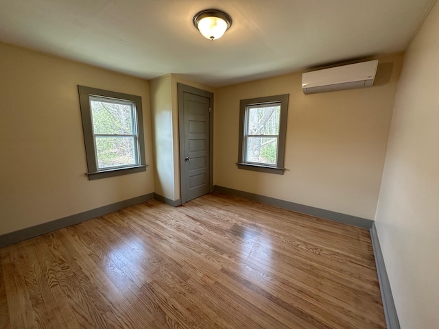 72 Seal Cove Rd, Southwest Harbor, ME 04679 - unfurnished bedroom featuring an AC wall unit, light wood-style flooring, multiple windows, and baseboards