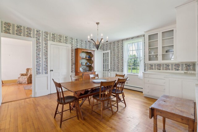 538 Malbons Mills Rd, Skowhegan, ME 04976 - dining area with wallpapered walls, baseboard heating, a chandelier, light wood-style flooring, and wainscoting