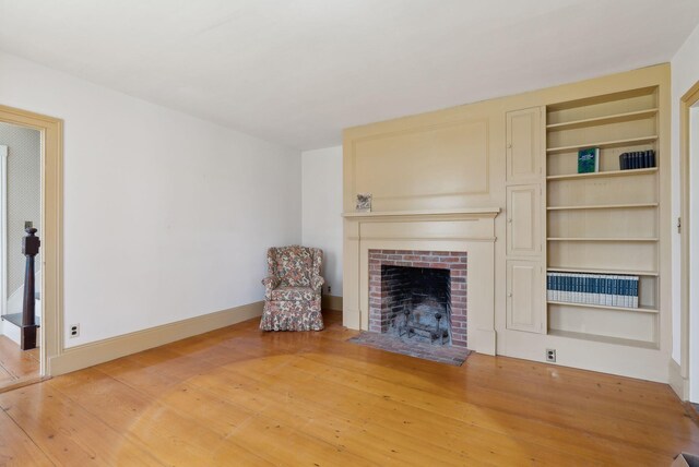 538 Malbons Mills Rd, Skowhegan, ME 04976 - unfurnished living room featuring light wood-style flooring, a fireplace with flush hearth, built in shelves, and baseboards