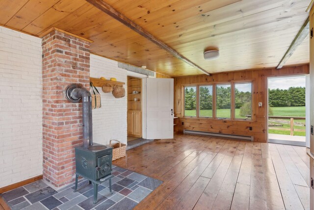 538 Malbons Mills Rd, Skowhegan, ME 04976 - unfurnished living room featuring baseboard heating, wood ceiling, wood-type flooring, a wood stove, and brick wall