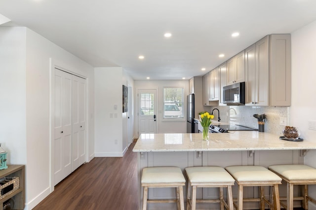 15 Francis St Unit 10, Old Orchard Beach, ME 04064 - kitchen featuring appliances with stainless steel finishes, dark wood-style flooring, light stone countertops, a kitchen bar, and a peninsula