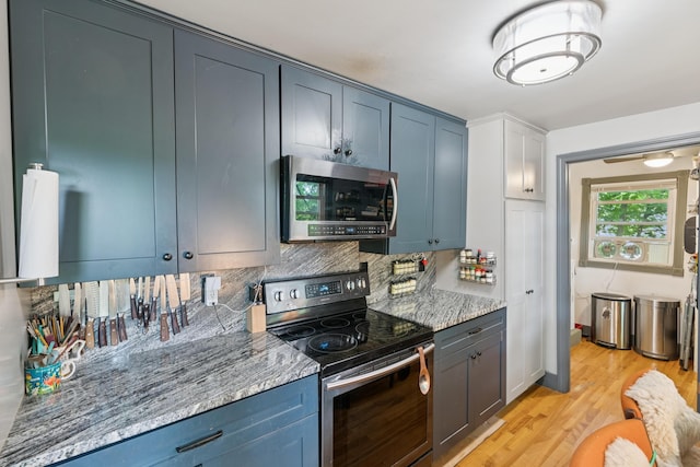 176 Second St, Auburn, ME 04210 - kitchen featuring stainless steel appliances, tasteful backsplash, light wood-style floors, blue cabinets, and light stone countertops
