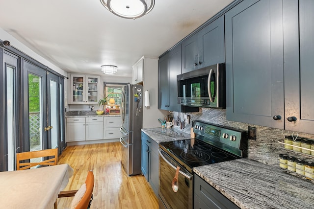 176 Second St, Auburn, ME 04210 - kitchen with stainless steel appliances, decorative backsplash, glass insert cabinets, light wood-type flooring, and light stone countertops