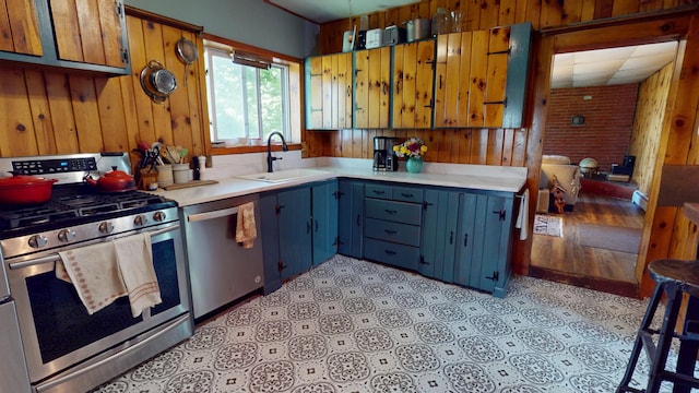 19 Russell St, Bangor, ME 04401 - kitchen with stainless steel appliances, a sink, wood walls, light countertops, and blue cabinetry