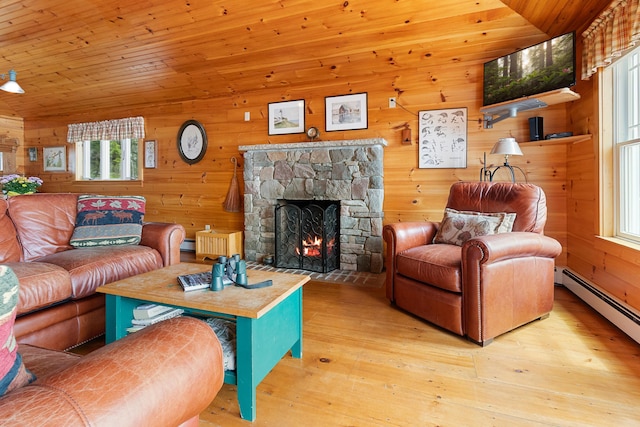 21 Linekin Rd, Boothbay Harbor, ME 04538 - living area featuring healthy amount of natural light, a stone fireplace, wooden walls, wood finished floors, and a baseboard radiator