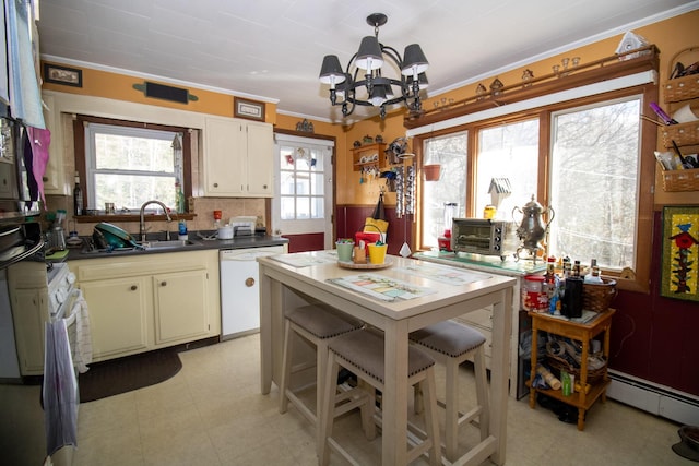 kitchen with white appliances, crown molding, a sink, dark countertops, and a chandelier