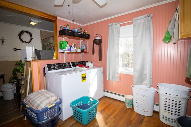 laundry area with washer and dryer, baseboard heating, ceiling fan, wood finished floors, and crown molding