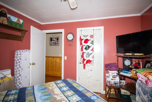 bedroom with ornamental molding and wood finished floors