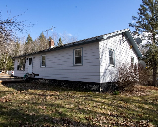 back of house featuring a chimney and a yard