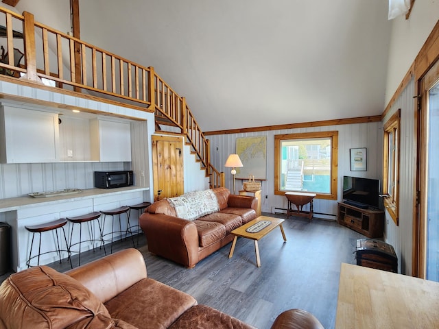 61 W Shore Rd, Harpswell, ME 04079 - living area with high vaulted ceiling, a baseboard heating unit, wood finished floors, wooden walls, and stairway