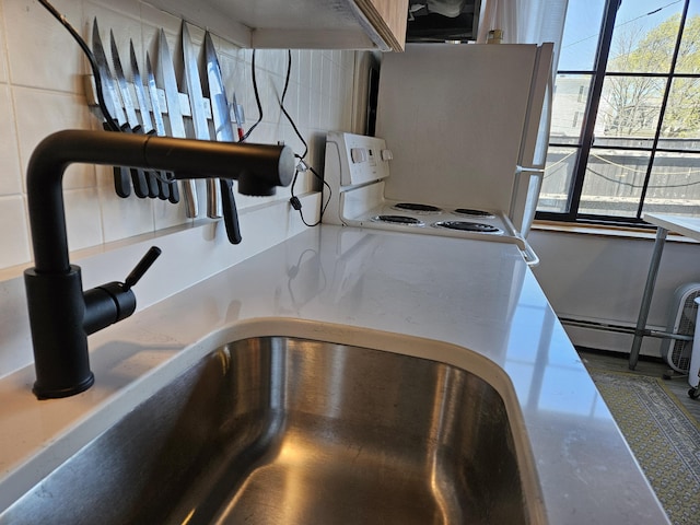 58 Cedar St, Bangor, ME 04401 - kitchen view of backsplash, a sink, light countertops, and a baseboard radiator