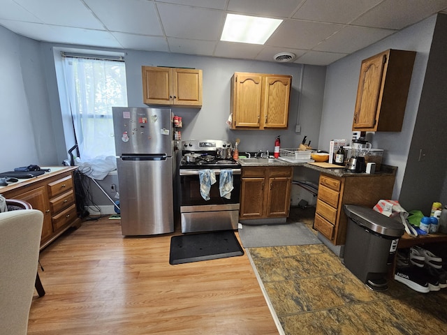 58 Cedar St, Bangor, ME 04401 - kitchen with stainless steel appliances, a paneled ceiling, light wood-style flooring, a sink, and brown cabinetry