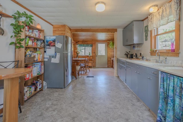 283 School St, Weld, ME 04285 - kitchen with freestanding refrigerator, wooden walls, gray cabinetry, light flooring, and light countertops