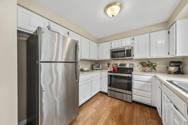 4 Oakview Dr Unit 4, Cape Elizabeth, ME 04107 - kitchen with appliances with stainless steel finishes, wood finished floors, light countertops, white cabinetry, and a textured ceiling