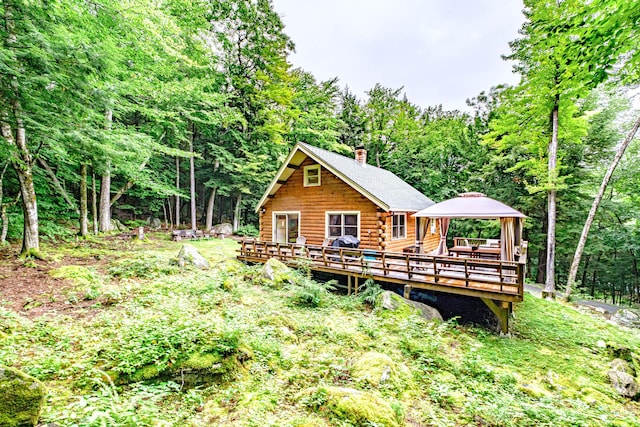 134 Valhalla Ln, Norway, ME 04268 - rear view of house featuring a gazebo, log siding, a view of trees, a chimney, and a deck