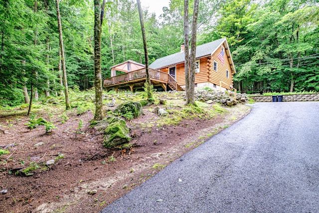 134 Valhalla Ln, Norway, ME 04268 - view of front of home with log exterior, a wooden deck, a chimney, and a wooded view
