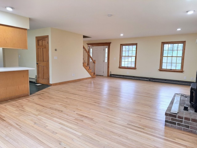 20 Brandywine Cir, Auburn, ME 04210 - unfurnished living room featuring a baseboard heating unit, a wood stove, light wood-style floors, stairway, and recessed lighting