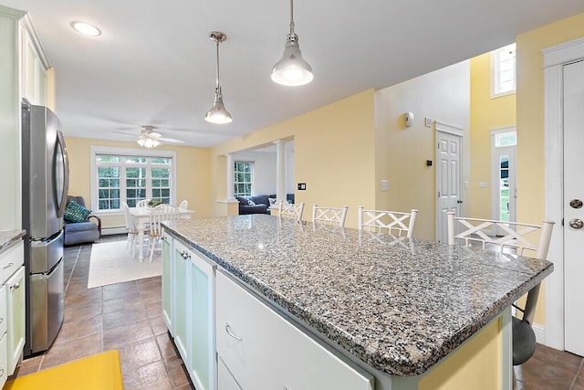 22 Lindas Way, Manchester, ME 04351 - kitchen featuring freestanding refrigerator, open floor plan, a kitchen island, ceiling fan, and dark stone counters