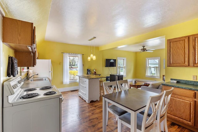 66 Beechwood St, Thomaston, ME 04861 - kitchen with white electric range oven, brown cabinetry, wood-type flooring, healthy amount of natural light, and a textured ceiling