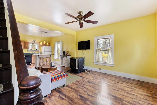 66 Beechwood St, Thomaston, ME 04861 - living room with wood finished floors, a ceiling fan, baseboards, and a wood stove