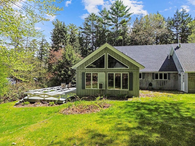 66 Brickett Point Ests, Oakland, ME 04963 - back of property featuring board and batten siding, a shingled roof, a lawn, and a deck