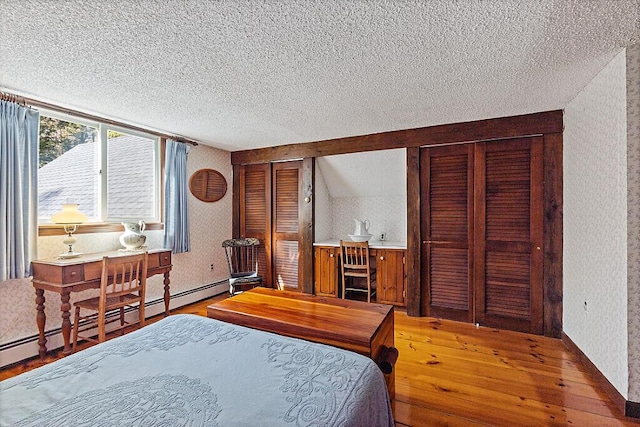 66 Brickett Point Ests, Oakland, ME 04963 - bedroom featuring wallpapered walls, multiple closets, a textured ceiling, wood-type flooring, and a baseboard heating unit
