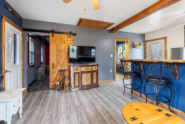 194 Birch Ln, Unity, ME 04988 - living room with wood finished floors, baseboards, a ceiling fan, beam ceiling, and a barn door