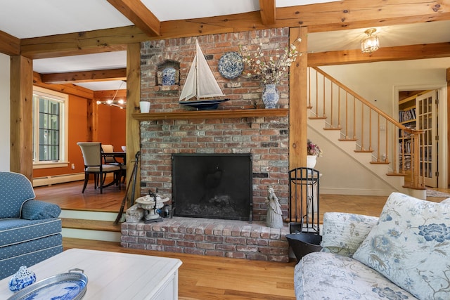 298 Ocean Ave, Kennebunkport, ME 04046 - living area with beamed ceiling, a baseboard radiator, stairway, wood finished floors, and a brick fireplace