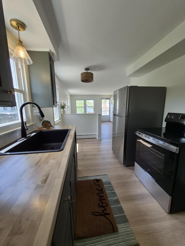 kitchen with electric range oven, a sink, light wood-style flooring, light countertops, and decorative light fixtures