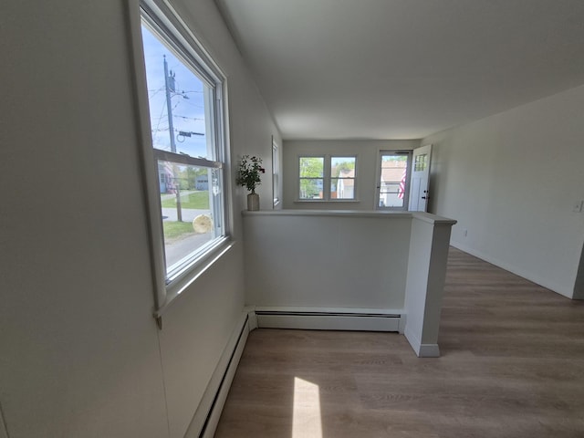 empty room featuring a baseboard heating unit, wood finished floors, baseboard heating, and baseboards