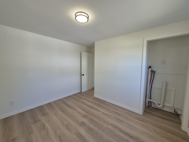 unfurnished room with light wood-type flooring and baseboards