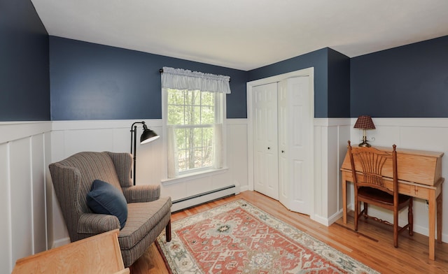28 Winchester Ct Unit 36, Kennebunk, ME 04043 - sitting room with a baseboard radiator, wainscoting, light wood-style flooring, and a decorative wall