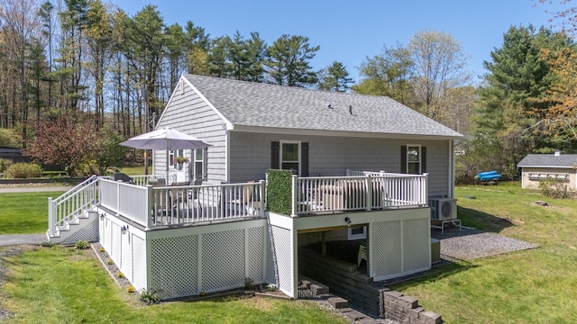 back of house with a shingled roof, a wooden deck, a cooling unit, and a lawn