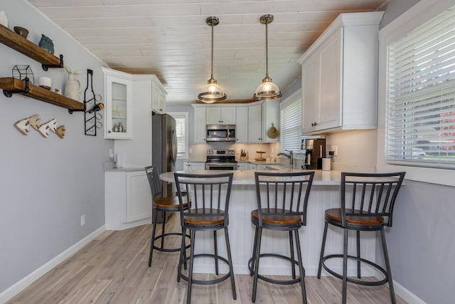 kitchen featuring stainless steel appliances, a peninsula, light wood-style floors, white cabinets, and wood ceiling
