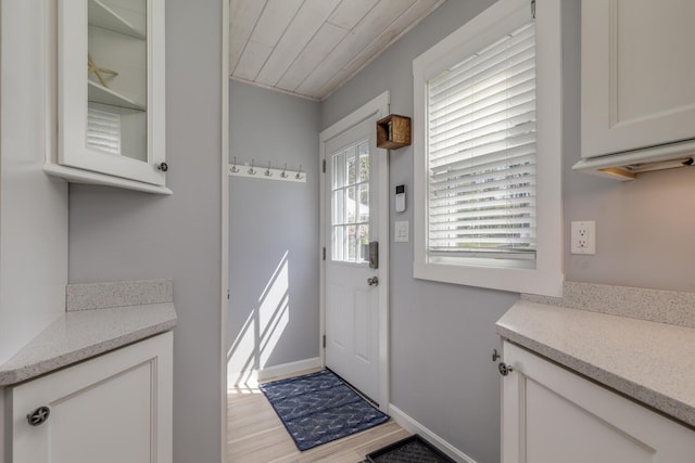 entryway featuring light wood finished floors, wood ceiling, and baseboards