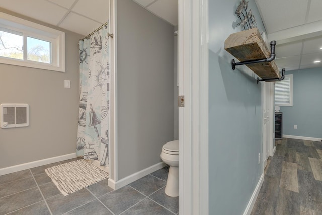 full bath with toilet, baseboards, a shower with shower curtain, and heating unit